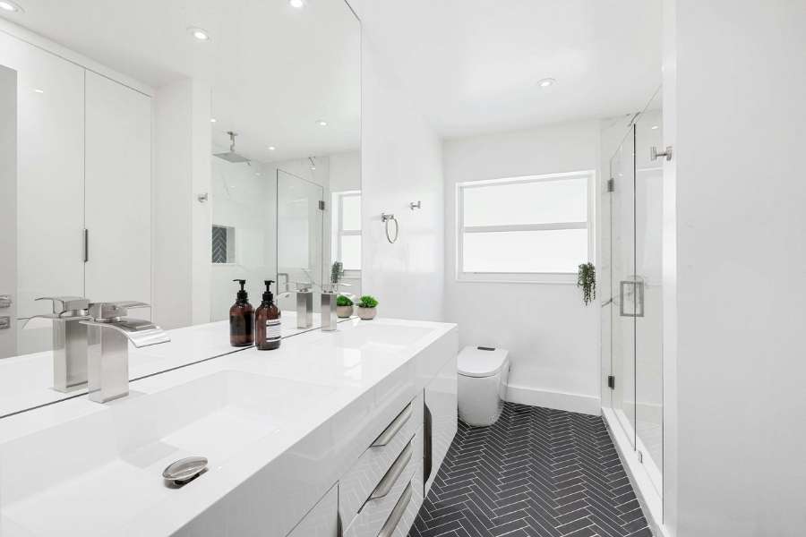 Modern bright bathroom with dark herringbone slip-resistant bathroom floor tiles.