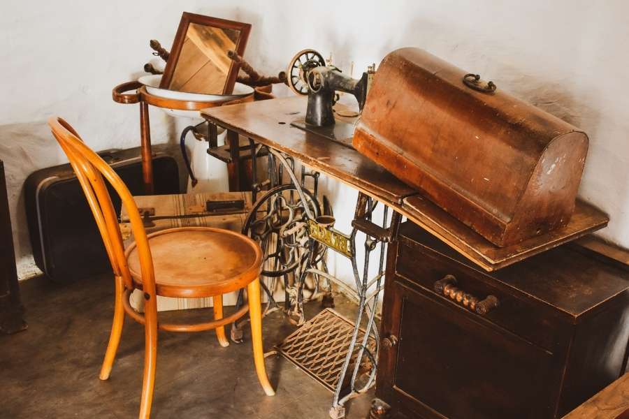 A collection of antique workshop pieces featuring vintage wooden furniture and an old sewing machine.